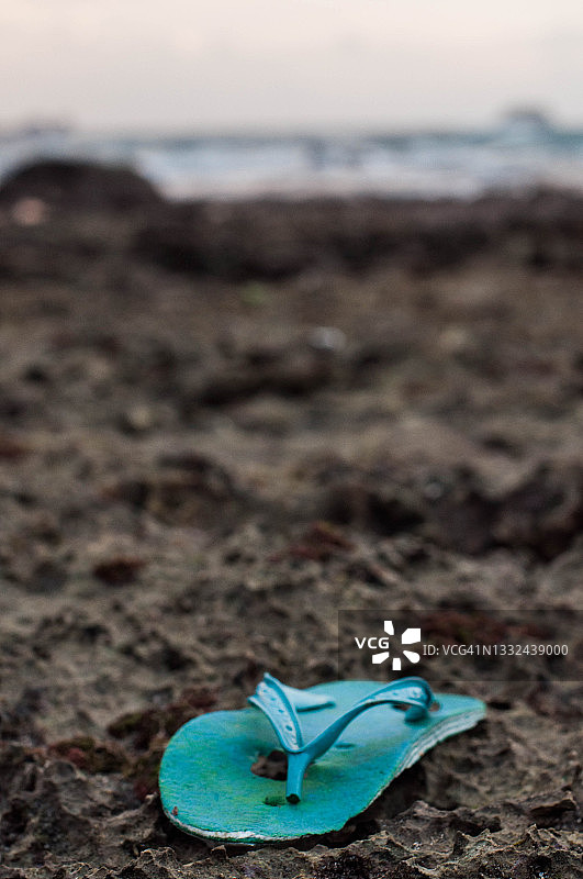 被遗弃在沙滩上的绿色拖鞋垃圾图片素材