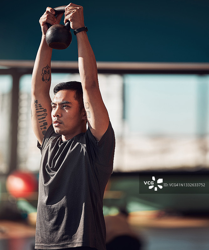 一个年轻人在健身房用壶铃锻炼图片素材