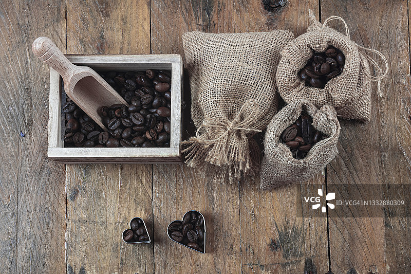 烤咖啡豆在麻袋和咖啡豆安排在心脏形状的乡村木制背景。图片素材