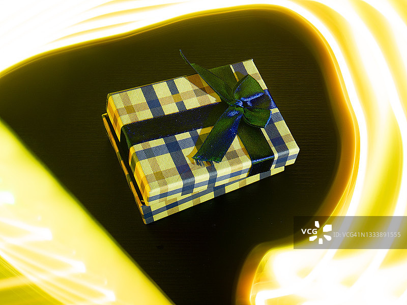 小礼品盒上有一条丝带，周围是黄色的弧形灯。图片素材