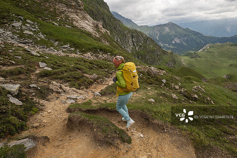 一名年轻女子在瑞士阿尔卑斯山徒步旅行，她沿着小路前行图片素材