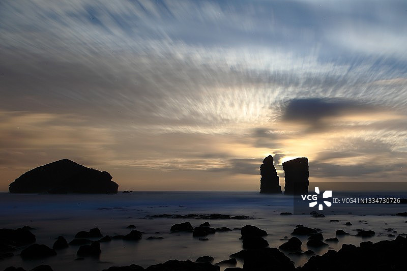 落日海景两大块岩石的剪影，多云的天空图片素材
