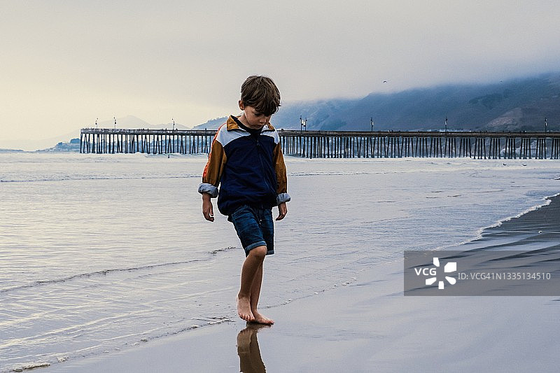 小男孩在海滩上散步图片素材