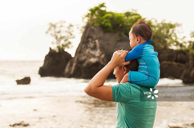 一位东南亚的父亲在海滩上抱着男婴图片素材