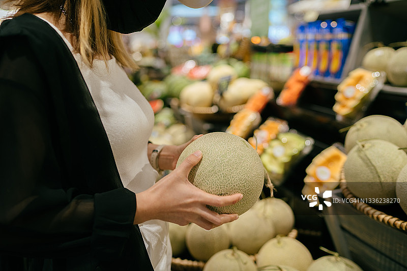 一名戴着帽子的妇女来到一家商店购买新鲜农产品。图片素材