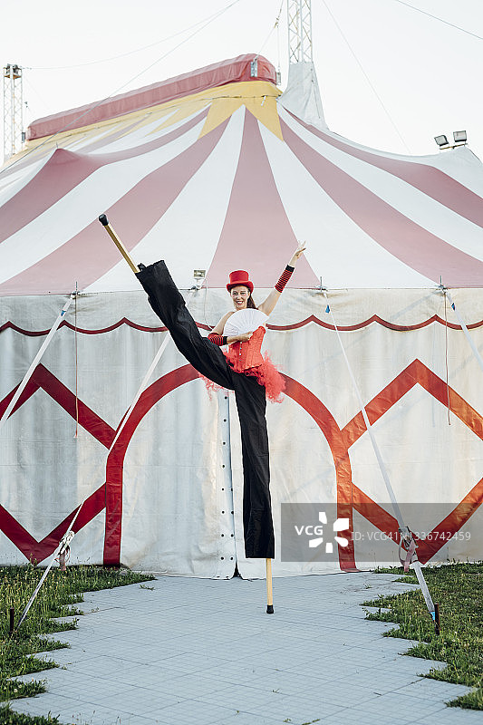 女艺人手持扇子，高跷站在帐篷前图片素材
