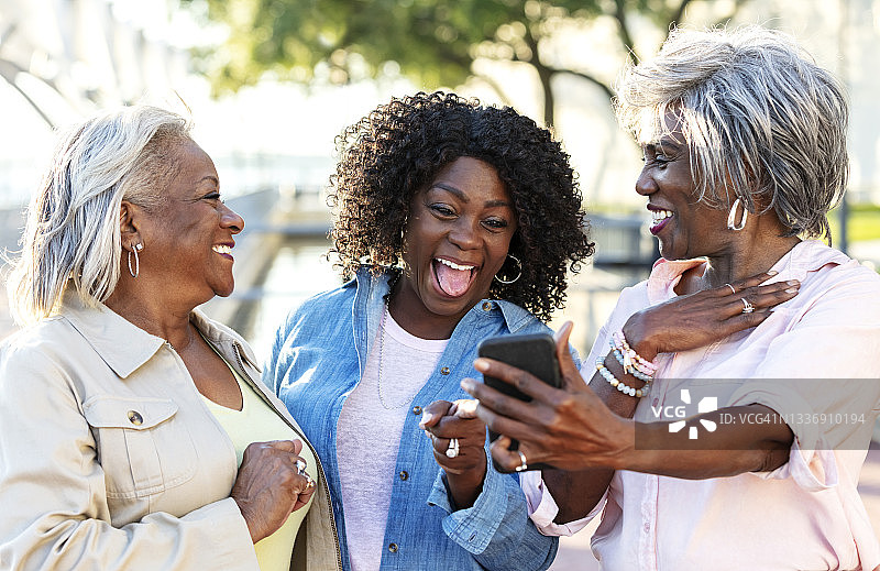 非裔美国妇女大笑着，看着手机图片素材