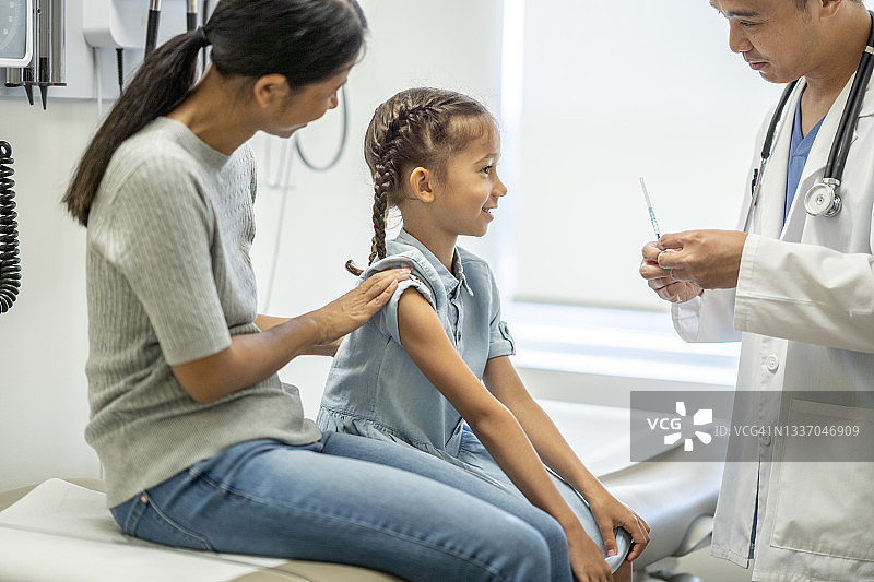一个小学女孩在医生的办公室里打流感疫苗图片素材