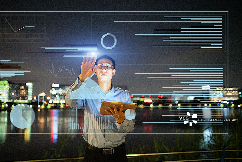 亚洲人在晚上使用虚拟现实屏幕进行触摸操作图片素材