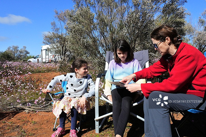 澳大利亚家庭围坐在户外露营地，计划在大自然中远足图片素材