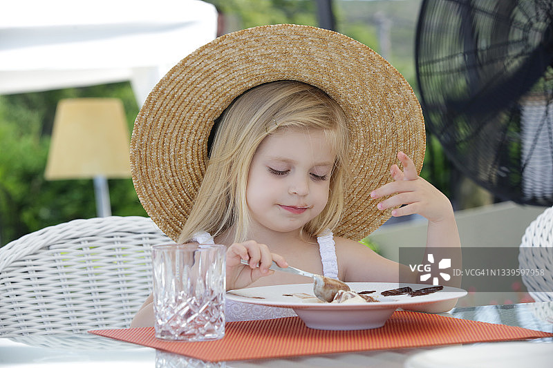 可爱的小女孩在户外餐厅吃甜点图片素材