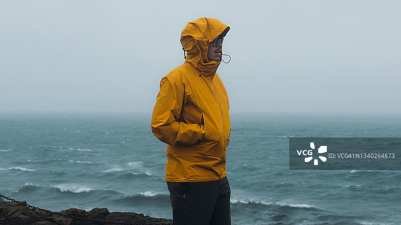 在冰岛，一名男子走在暴风雨的海滩上，感到敬畏图片素材