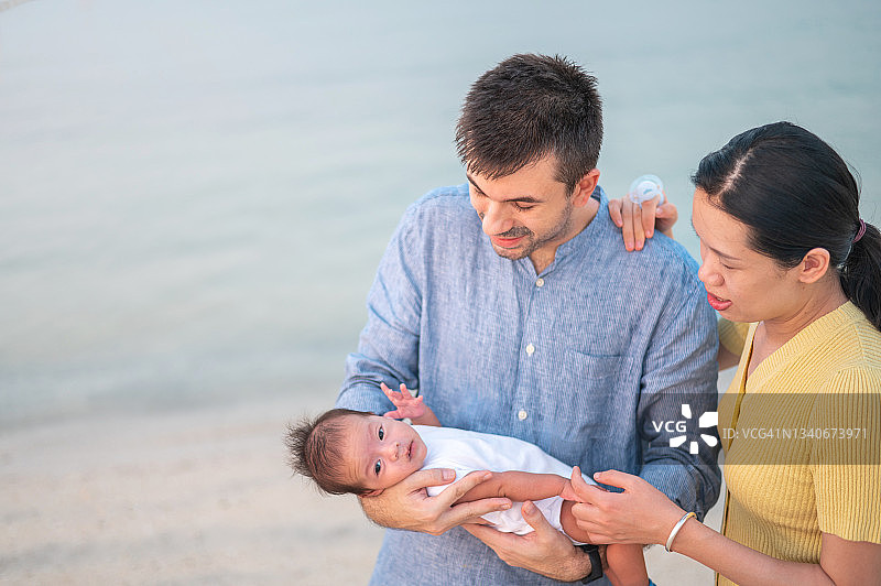 幸福的家庭和一个刚出生的婴儿在海边图片素材