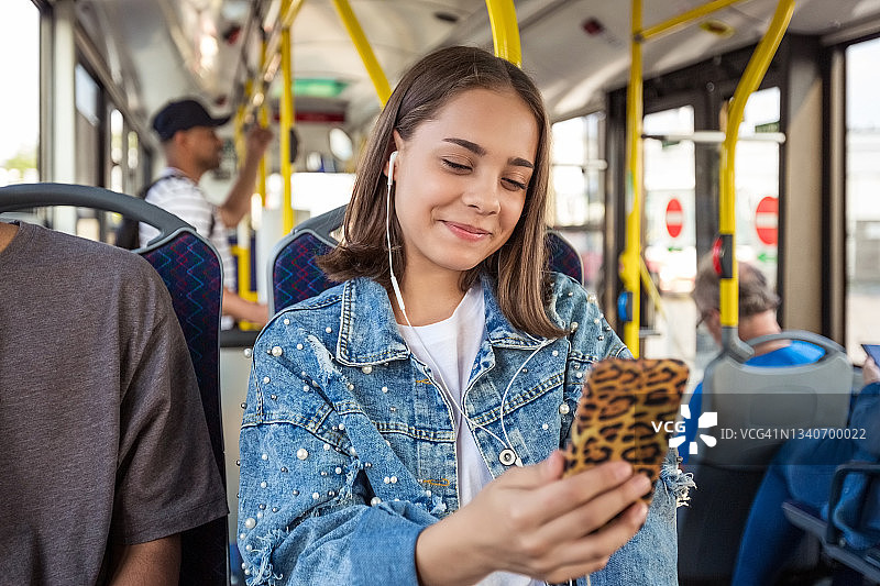 十几岁的女孩在公共交通上使用智能手机图片素材