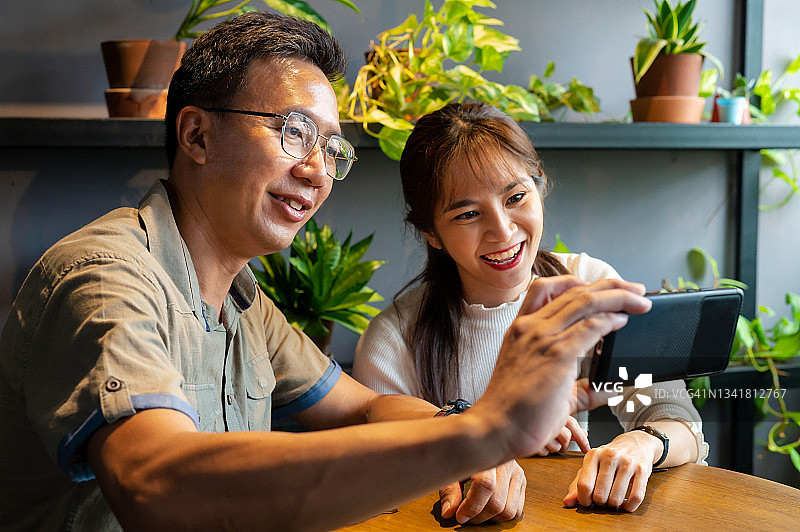 亚洲中国企业夫妇视频通话客户端与智能手机在办公室图片素材