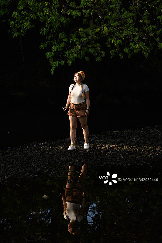 女孩独自站在水中倒影的森林里图片素材