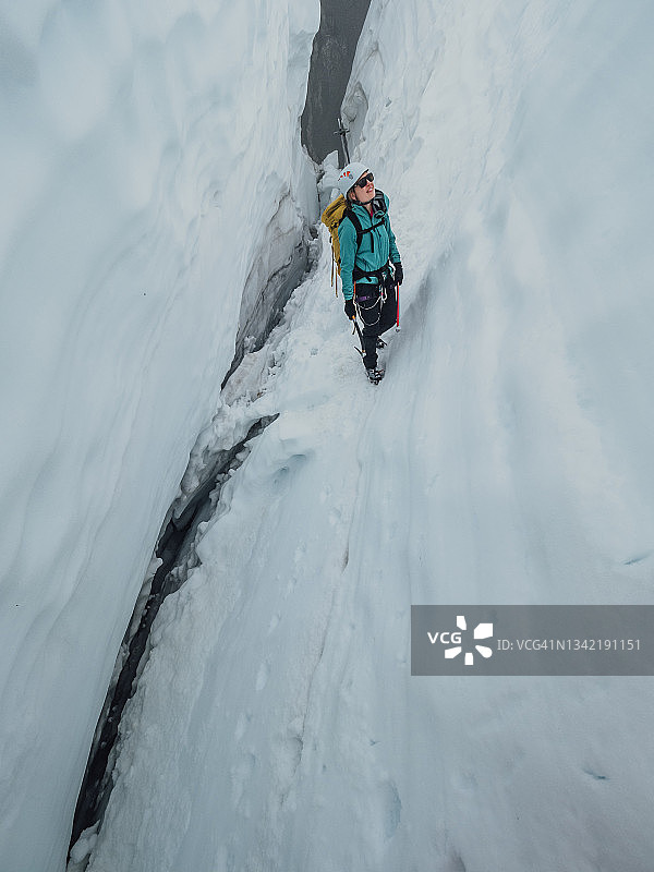一名女登山者爬过冰川上一个很深的裂缝图片素材