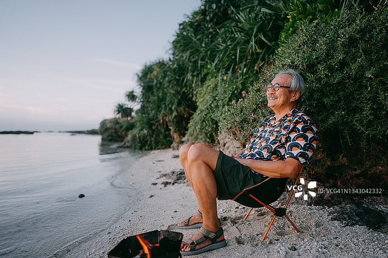日落时分，快乐的老人坐在海滩露营地图片素材