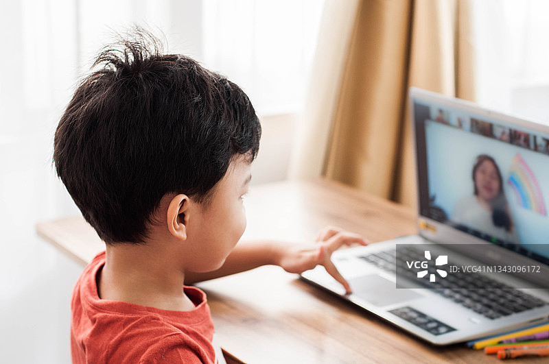 一名东南亚男童在冠状病毒大流行期间使用笔记本电脑进行家庭教育图片素材