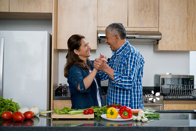 快乐的成人夫妇一起在家做饭，在厨房跳舞图片素材