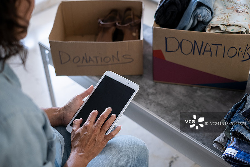 一名妇女正在为慈善机构准备装衣服的捐款箱图片素材