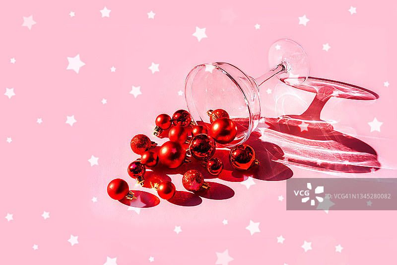 鸡尾酒杯和圣诞装饰红球在淡粉色的背景。图片素材
