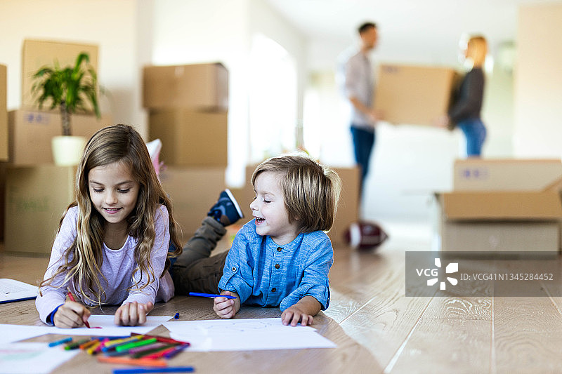 搬到新公寓后，快乐的孩子们在地板上涂色。图片素材
