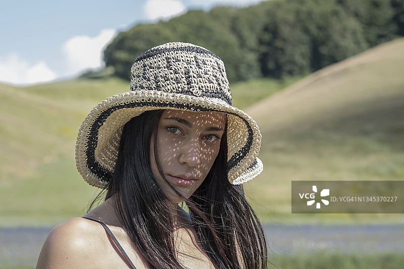在意大利翁布里亚的Norcia，一个戴着草帽的黑发女孩的肖像图片素材