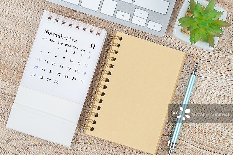 2022年11月月历台，顶视图日历和钢笔，笔记本在木桌背景。图片素材
