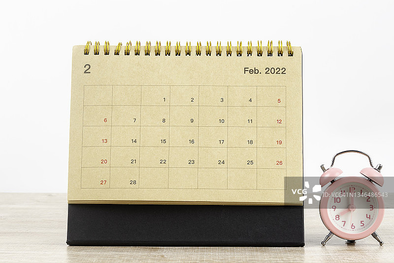 2022年2月日历桌，家庭办公室木桌上的日历桌和闹钟。图片素材