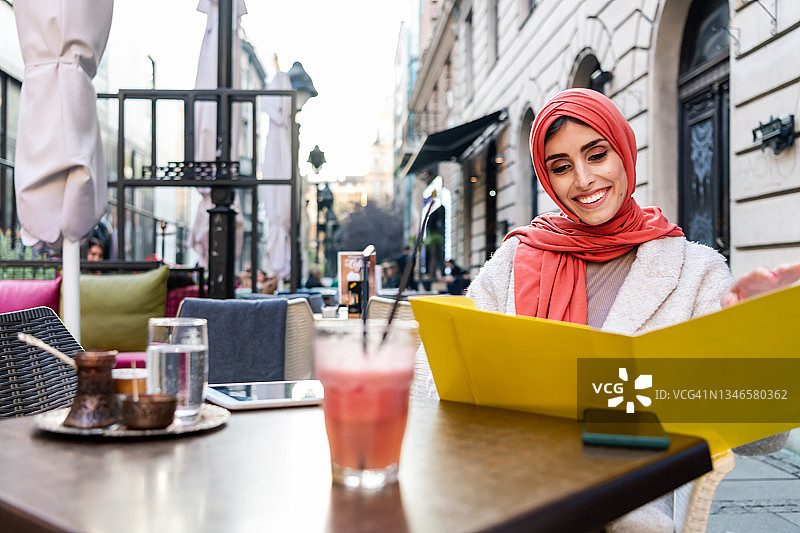 一名身穿穆斯林服装、戴着头巾的妇女在一家咖啡馆工作图片素材
