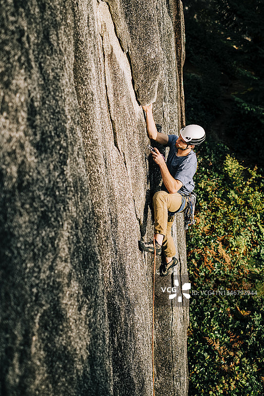 男性攀岩者在攀爬困难路线的中途将一件攀岩设备放入岩石中图片素材