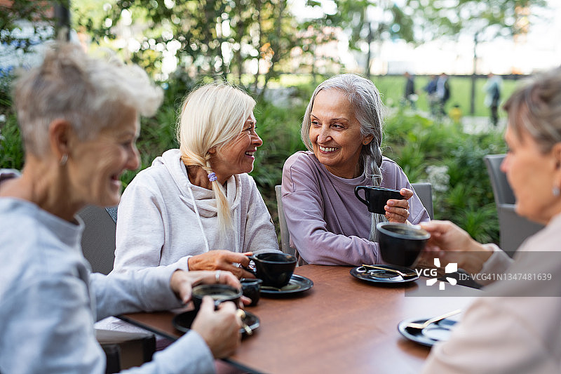 在café，一群快乐的老年妇女在户外运动后坐着聊天。图片素材