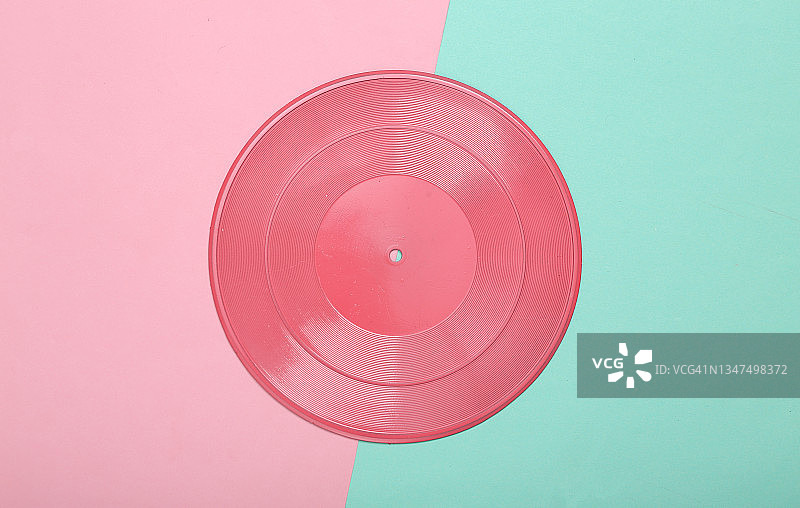 创造性的音乐布局。粉红色的黑胶唱片在粉红色的蓝色背景。极简主义。平的。前视图。图片素材