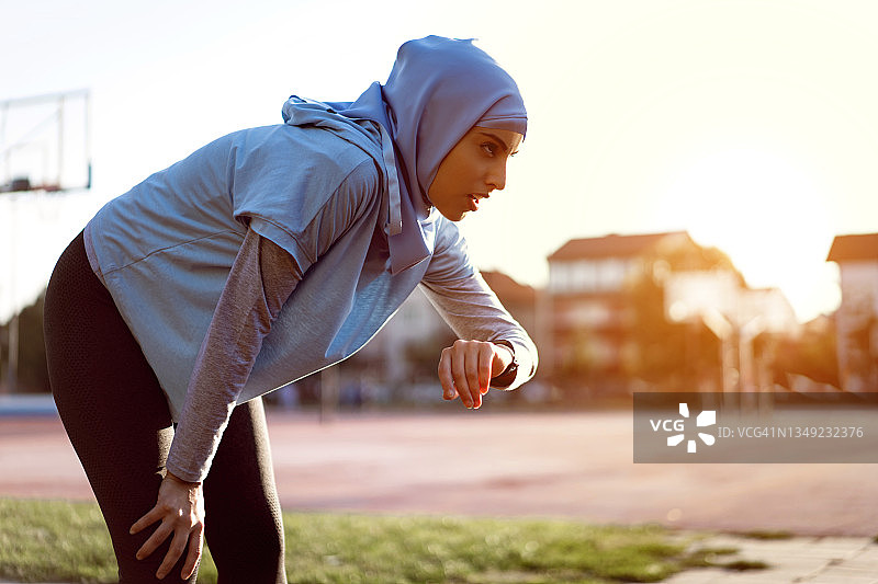 现代穆斯林女运动员正在用健身追踪器检查自己的脉搏图片素材