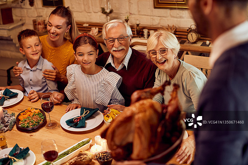 幸福的几代家庭在餐桌上享用感恩节火鸡大餐。图片素材