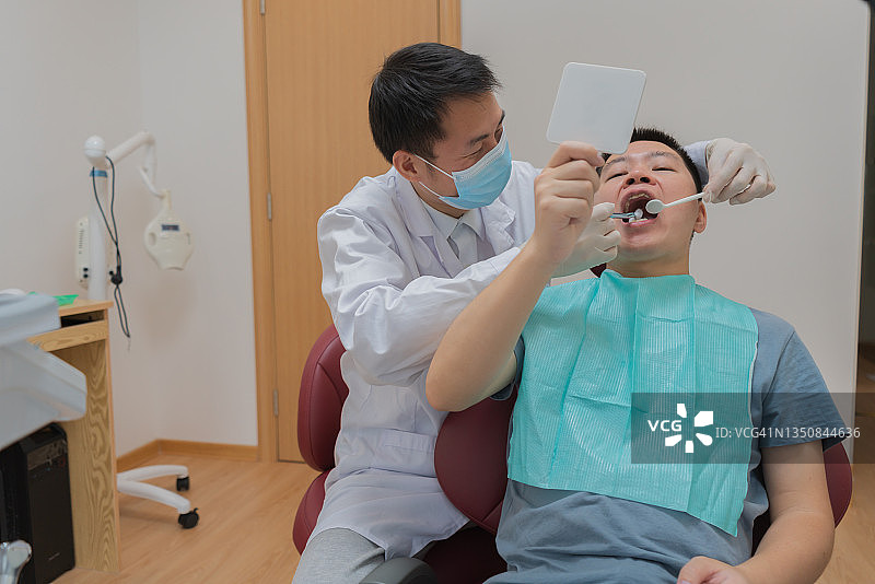 亚洲医生对病人的牙齿进行护理检查图片素材