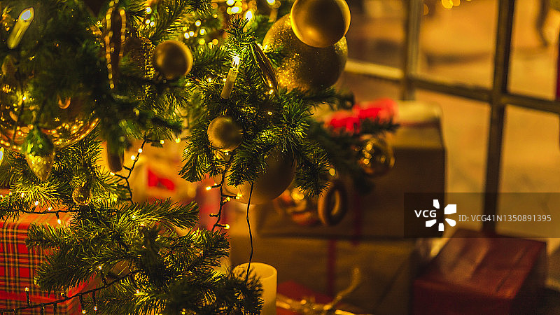 圣诞节和新年室内装饰。绿树上装饰着玩具、礼品、礼品盒、闪烁的花环、灯饰。壁炉和圣诞树。舒适的圣诞气氛图片素材