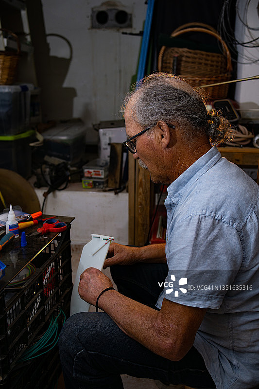 侧面的成熟男子正在他的车库的小车间为手工制作冲浪板的一部分。图片素材