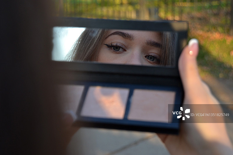 一个年轻女人在化妆镜中的折射。图片素材