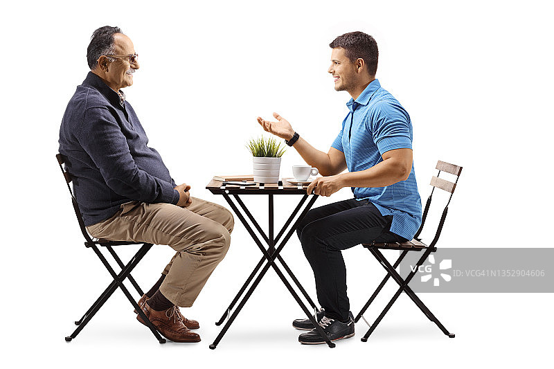 一个年轻人坐在咖啡馆里和一个成熟的男人聊天图片素材