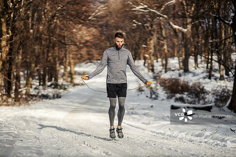 健康的运动员在雪天在森林里跳绳。冬季健身，有氧运动图片素材