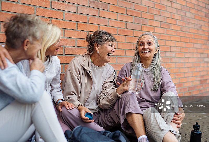 一群兴高采烈的老年妇女在户外锻炼后坐在一起聊天。图片素材