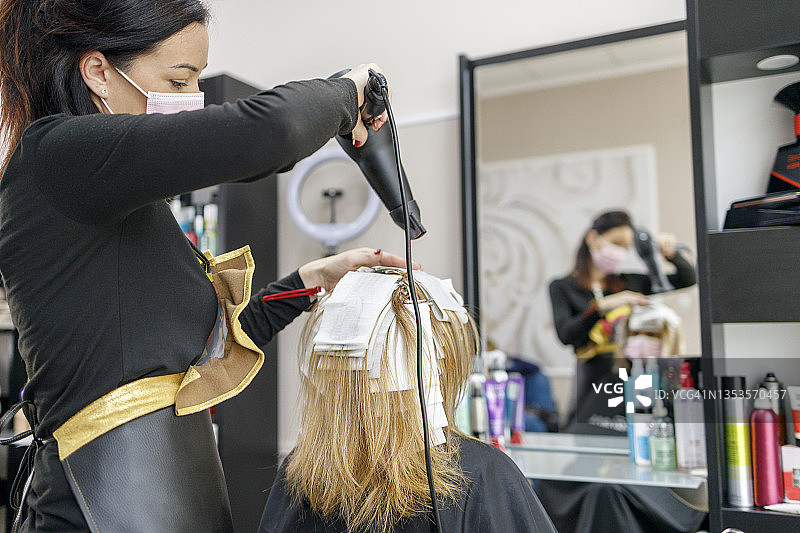 美发师使用特殊的技术，精心吹干含有染发剂的箔片，以获得更好的效果图片素材