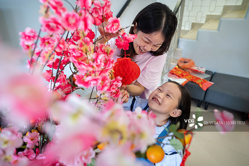 年轻的亚洲女孩帮助妈妈挂中国新年装饰图片素材