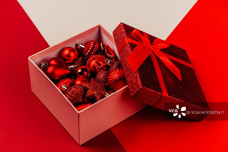 打开红色的礼盒，大蝴蝶结和红色发光的圣诞玩具。图片素材
