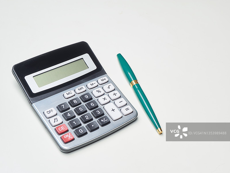 计算器和钢笔在白色的桌子上。金融的概念。图片素材
