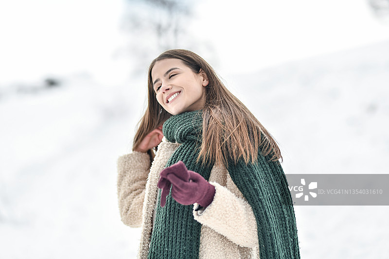 微笑的女人在温暖的衣服享受宁静的山雪图片素材