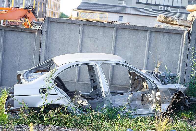 废车场里报废的旧汽车。后院水泥墙附近被摧毁的金属车辆，侧视图图片素材