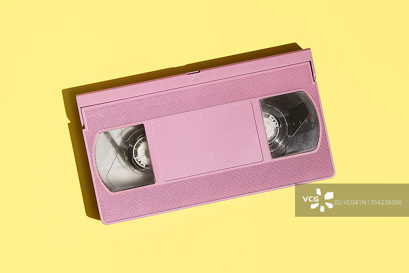 黄色背景上的粉红色VHS磁带图片素材